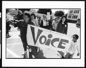 Banner held by woman and child in parade, Industrial Areas Foundation, Los Angeles, 1996