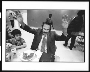 Man with hands in the air over a plate of food and onlookers, Union Rescue Mission, Los Angeles, 1996