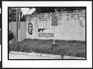 A wall in San Salvador with a painting of Che Guevara, an AK-47, and the words, Insurrection