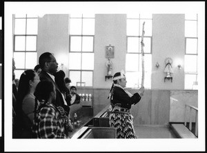 Woman carrying cross leading procession in church, Los Angeles, 1999