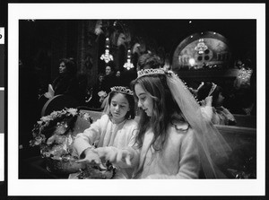 Two flower girls in tiaras with flower baskets comparing gloves, Los Angeles, 1999