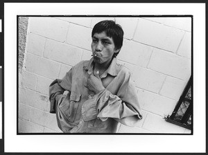 Young man of Hispanic origin smoking a crack pipe, downtown San Salvador