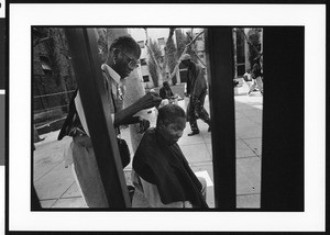 Homeless woman shaving another homeless person's head, Union Rescue Mission, Los Angeles, 1996