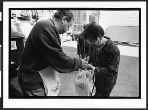 Man of Chinese origin giving a bag of food to woman of Chinese origin, Cameron House, Chinatown, San Francisco, California, 2002