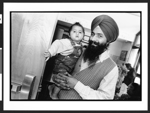 Sikh man with young child at prayer service of National Sikh Foundation at Travilah Elementary School, North Potomac, Maryland, 2002