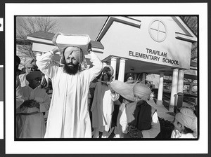 Sikh man carrying the Adi Granth (sacred texts) on his head at conclusion of prayer service of National Sikh Foundation, Travilah Elementary School, North Potomac, Maryland, 2002