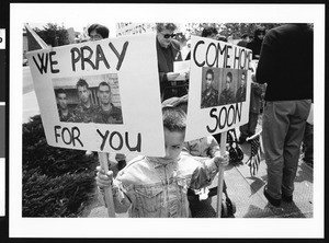 Young boy with signs at demonstration, Los Angeles, 1999