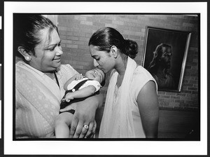 Two women of Indian origin , one kissing a baby being held by the other. Naperville Church of the Brethren, 2002