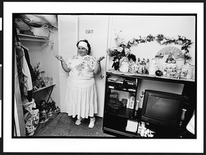 Marissa, a Santeria priestess, also known as a lyalrishas, or mother of Orisha, the Santeria god, standing in front of her altar in her home, 399 NW 72nd Avenue & 3rd Street, Miami, Florida, 2002