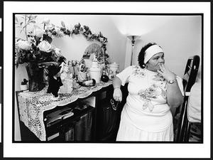 Marissa, a Santeria priestess, also known as a lyalrishas, or mother of Orisha, the Santeria god, standing in front of her altar in her home, 399 NW 72nd Avenue & 3rd Street, Miami, Florida, 2002