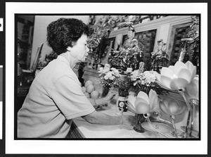 Woman of Chinese origin putting flowers on altar of Buddha, Ling Shen Ching Tze Temple, Chicago, Illinois, 2002