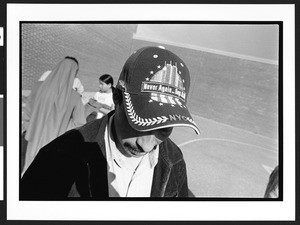 Man with "Never Again, Sept. 11" cap, outside, after Mass, Langley Park-McCormick Elementary School, Hyattsville, Maryland, 2002