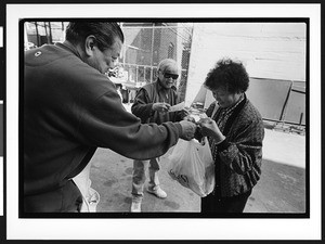 Man of Chinese origin giving a bag of food to woman of Chinese origin, Cameron House, Chinatown, San Francisco, California, 2002