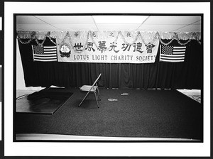 A stage with one chair and the banner "Lotus Light Charity Society" in the basement of the Ling Shen Ching Tze Temple, Chicago, Illinois, July 28, 2002