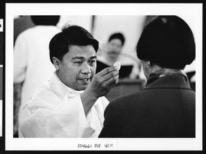 Priest giving host to woman, Los Angeles, 1999