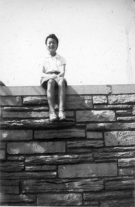 young woman sitting on wall