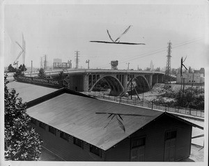 View of the north side of the new Spring Street bridge showing a municipal swimming pool in the foreground and Downtown Los Angeles in the background