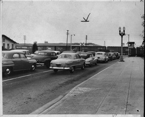 Autos on Los Feliz Rd., Glendale, held up while freight train passes, 1953