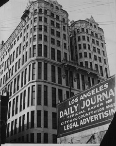 A low-angle view of the Hall of Records with a sign for the Los Angeles Daily Journal forgrounded, ca. 1930-1960