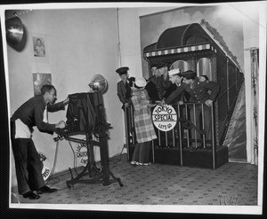 Studio photographer shooting a couple kissing on the back of a trolley car, 1943