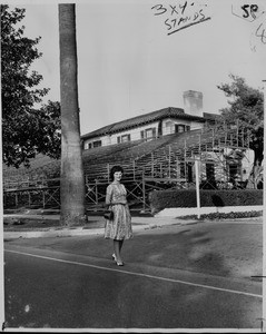 Tournament of Roses stenographer Joan Pulcifer passes grandstands along South Orange Grove Boulevard while going to work, 1961