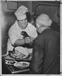 George Koines serves Robert Holland a turkey leg, Los Angeles, 1955