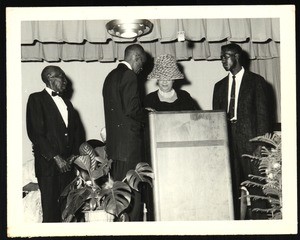 Unidentified people at a podium, in a tent, conversing