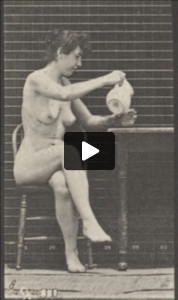 Nude woman sitting crossing legs and filing a goblet from a pitcher