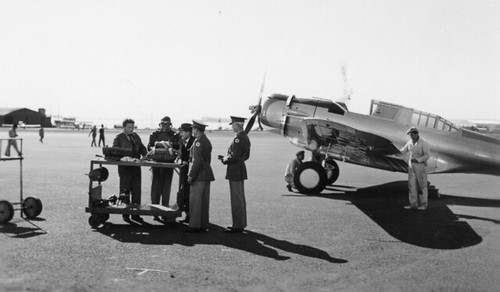 This is a still from the 1939 movie Test Pilot. Actors Spencer Tracy, Clark Gable and Lionel Barrymore are left to right at the table. The aircraft is a Northrop A-17A from the 17th Attack Squadron at March Field