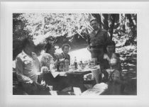 Five adults and one child enjoying a picnic under the trees, unknown