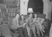 Two couples sitting on sofa, one man is a soldier, unknown