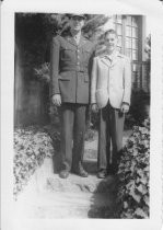 Sibling, brother, with soldier standing on steps outside house, unknown