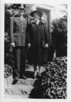 Mother with soldier standing on steps outside house, unknown