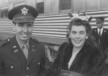 Military man and woman in front of train, unknown