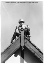 Firefighter putting up holiday lights on Mill Valley City Hall, 1983