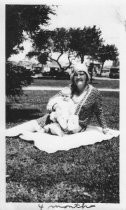 Baby, 4 months, sitting on what appears to be grandmother's lap on a blanket outside, unknown