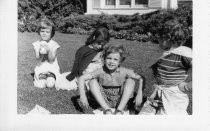 Four children playing outside on grass, 1954