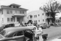 Woman getting into car with houses in background, unknown