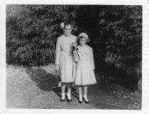 Carmel and Anita, two young girls standing out doors, Christmas 1957