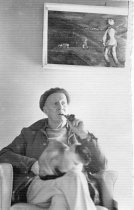 Dick Graveson seated with cat below painting, 1975