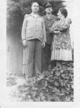 Mother and father with soldier standing on steps outside house, unknown