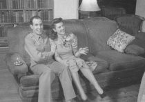 A couple sitting on sofa, man is a soldier, unknown