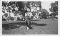 Woman standing outside, trees and cars in background, unknown