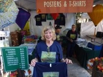 Fall Arts Festival volunteer displaying t-shirts, 2018