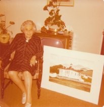 Irene Coffin sitting next to a print of Summit School, 1976