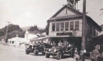 Firemen on fire trucks outside of station, early 1900s