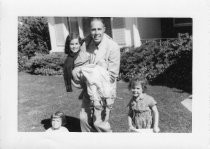 Father with three children playing outside on grass, 1954