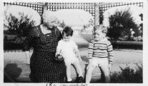 Grandmother sitting with an 18 month old baby and a child, unknown