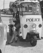 Molly MacGowan of the Mill Valley Police Department, sitting in the Cushman Police Vehicle, 1969