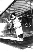 Photograph of a woman standing on a Mill Valley & Mt. Tam. Railway car